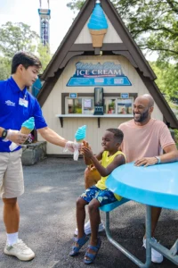 A Team Member handing a young boy an Udderly Blue Ice Cream cone.